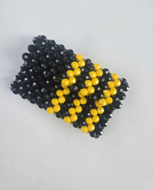 A handmade beaded wallet featuring a black and yellow pattern, inspired by bees, photographed on a plain light gray background.