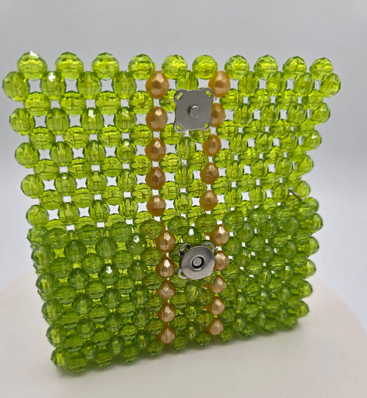 A handmade beaded wallet translucent sage green faceted beads, featuring a vertical decorative panel with gold opaque beads and silver-tone metal snap buttons.