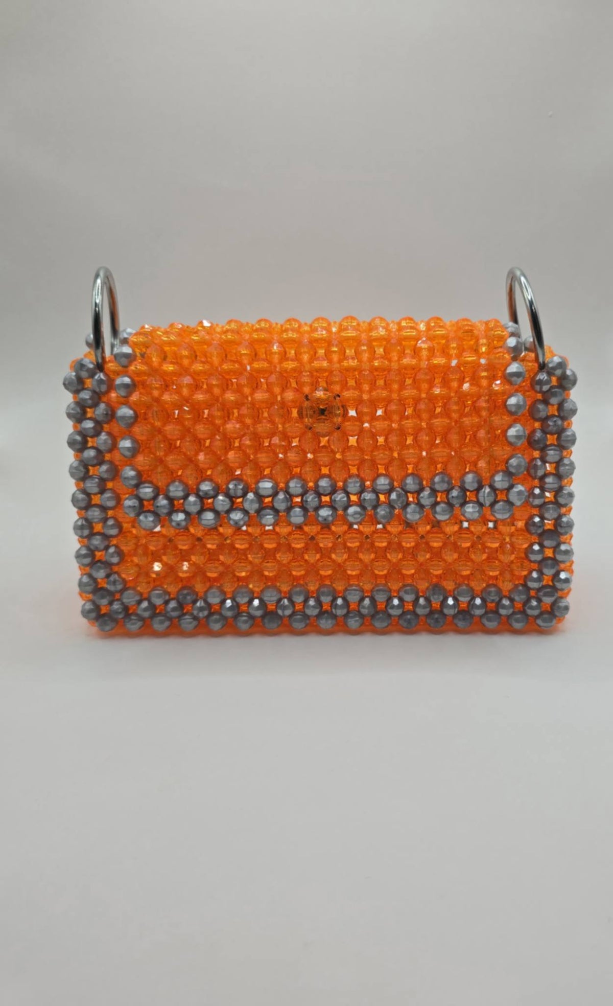 A small rectangular handbag covered in bright orange beads with a silver-gray beaded border and silver metal side rings, shown against a plain light gray background.