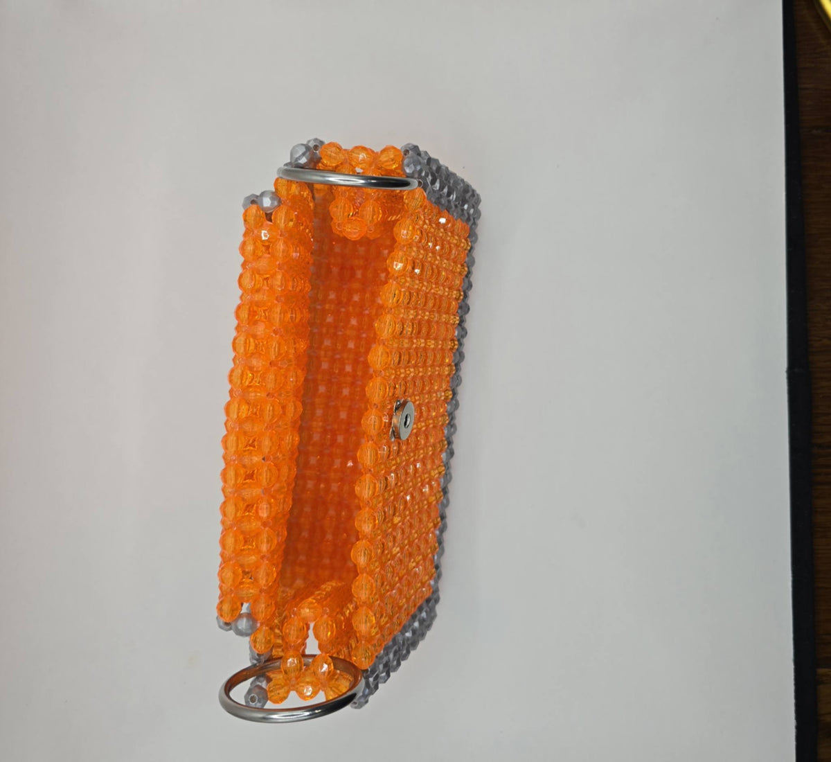 An orange beaded keychain case with silver metal rings and a silver side accent, shown against a plain white background.