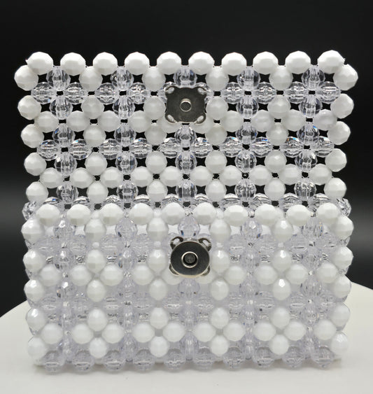 A beaded wallet made of white opaque and clear faceted acrylic beads, featuring two silver-tone metal snap buttons on the front, set against a dark background.